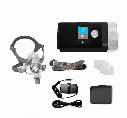 A sleep apnea treatment kit laid out on a white background, including a black and clear CPAP machine, a clear face mask with gray headgear, a coiled breathing tube, several white filter pads, a black power adapter with cable, and a black carrying case.